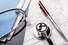 stethoscope and pen resting on a sheet of medical lab test results, with patient file and x-ray or mri film